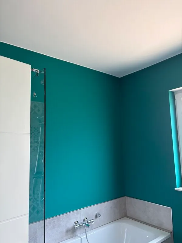 Badezimmerwand in Petrol, sauber abgesetzt an Badewanne und Dusche