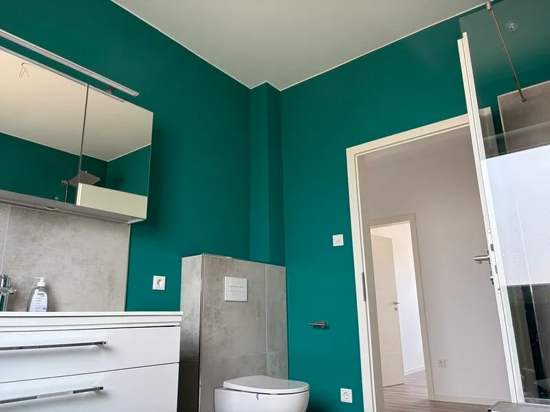 Badezimmer mit Wänden in kräftigem Petrol und weißen Möbeln