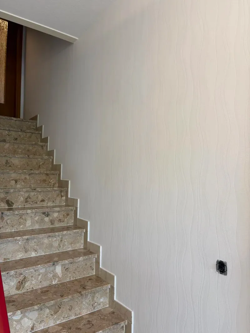 Treppenhaus mit heller Strukturtapete und Natursteintreppe