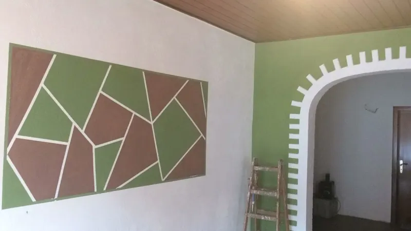 Wand mit aufgemaltem geometrischem Muster in Grün- und Brauntönen